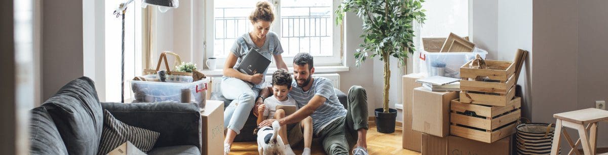 a family surrounded by packing boxes, playing with the dog.