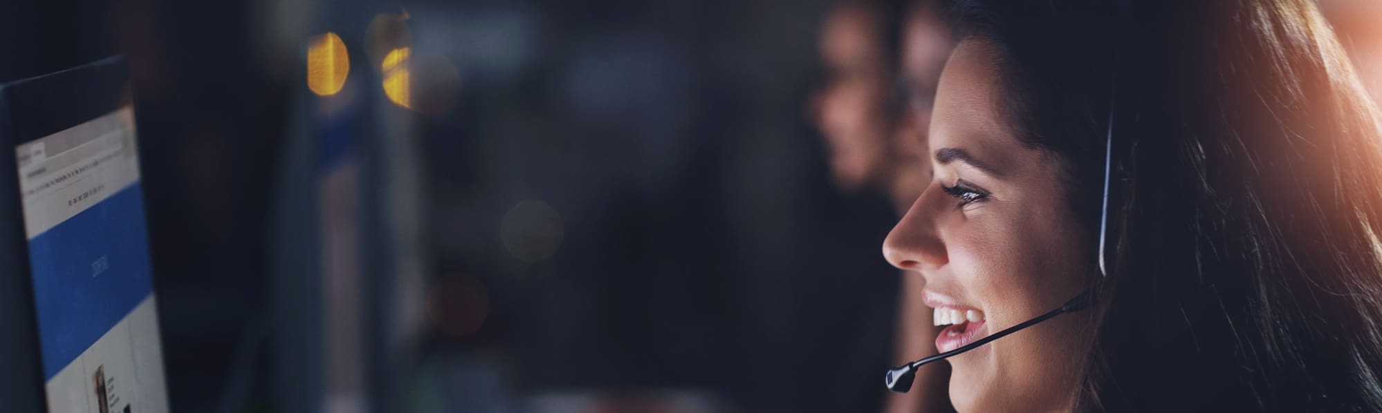 Woman smiling while talking on a headset and looking at her screen.