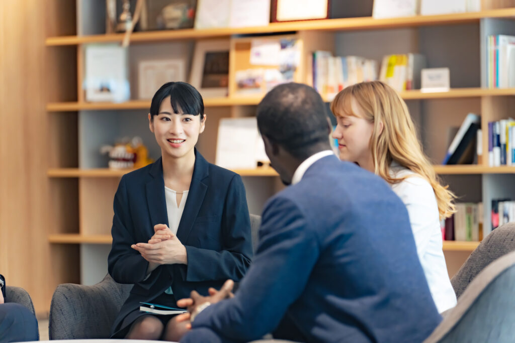 Three people seated together in a workspace, discussing and listening during a meeting.