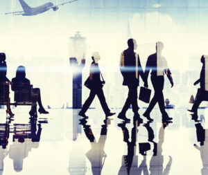 Silhouettes of people walking through an airport with reflections and a plane outside.