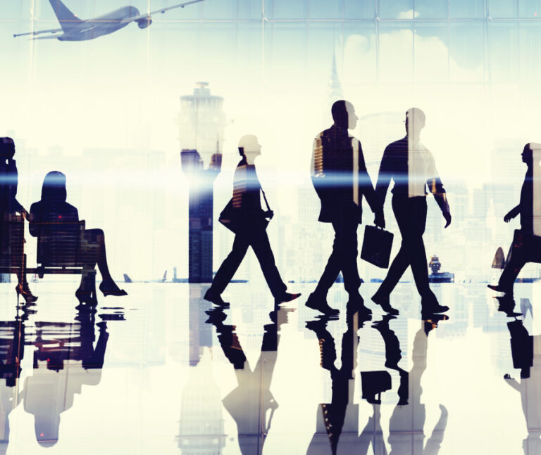 Silhouettes of people walking through an airport with reflections and a plane outside.